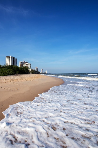 Hermosas playas de arena y olas espumosas Detrás hay un alto edificio blanco