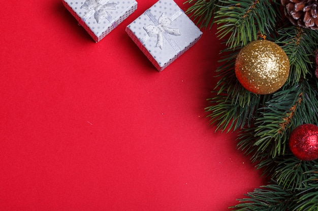 Hermosas ramas del árbol de Navidad con conos y juguetes sobre un fondo rojo.