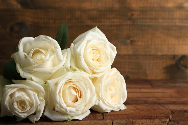 Hermosas rosas blancas en la mesa de madera