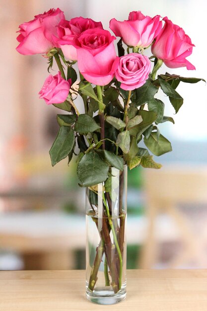 Hermosas rosas rosadas en un jarrón sobre la mesa en el fondo de la habitación