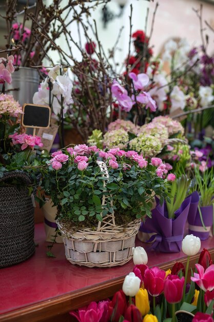 Hermosas rosas rosas en una canasta de mimbre Una variedad de flores de primavera Vitrina de una floristería