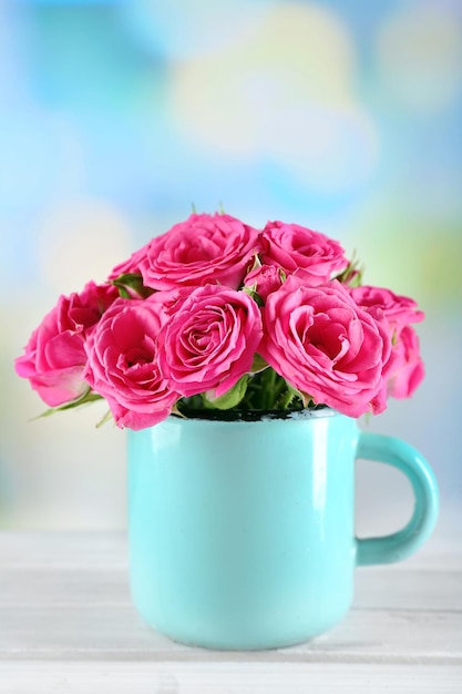 Hermosas rosas en taza sobre fondo brillante