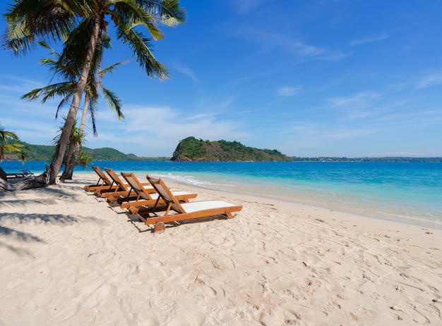 Hermosas sillas escénicas en la playa de arena blanca cerca de cocoteros con mar azul y cielo en la isla en verano, playa de relax en la isla de Rayang, Rayong, Tailandia