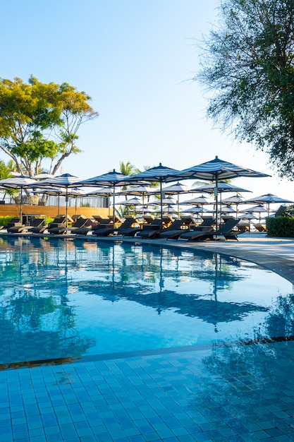 Foto hermosas sombrillas y sillas de lujo alrededor de la piscina al aire libre