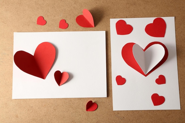 Hermosas tarjetas postales hechas a mano con corazones de papel sobre fondo de madera de color