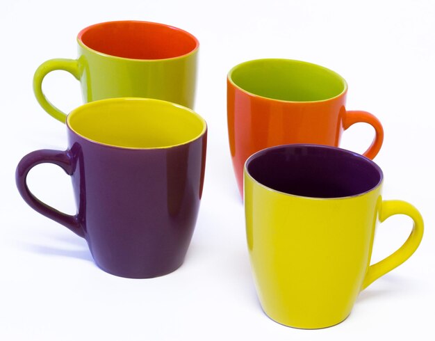 Hermosas tazas de porcelana de colores en fondo blanco.