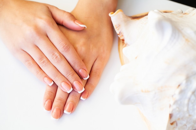 Hermosas uñas de mujer con manicura francesa, en estudio de belleza