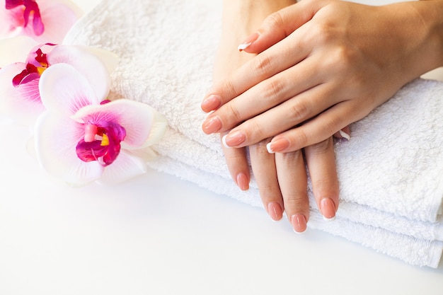 Hermosas uñas de mujer con manicura francesa, en estudio de belleza