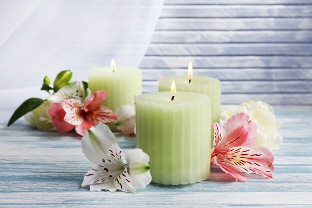 Hermosas velas con flores sobre fondo de madera