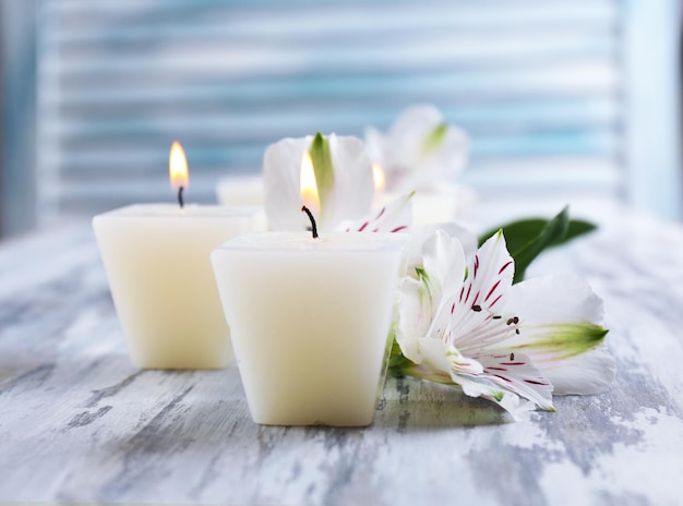 Hermosas velas con flores sobre fondo de madera