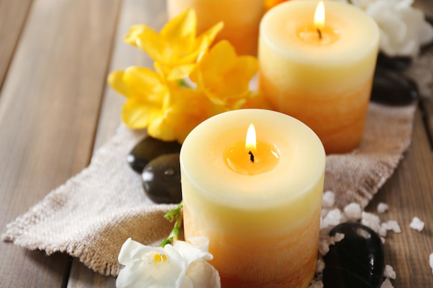 Hermosas velas con flores sobre fondo de madera