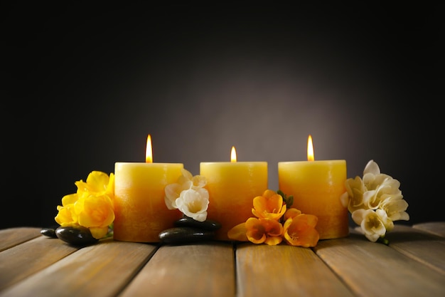 Hermosas velas con flores sobre fondo de madera