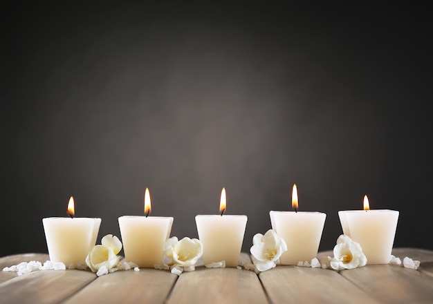 Hermosas velas con flores sobre fondo de madera