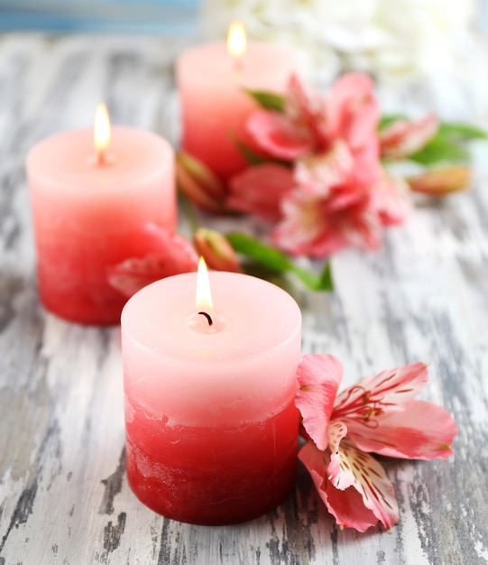 Hermosas velas con flores sobre fondo de madera