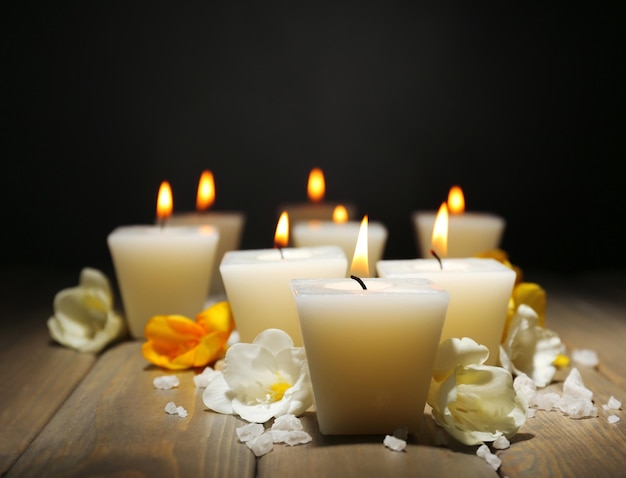 Hermosas velas con flores sobre fondo de madera