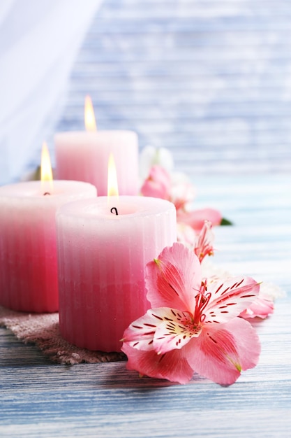 Hermosas velas con flores sobre fondo de madera