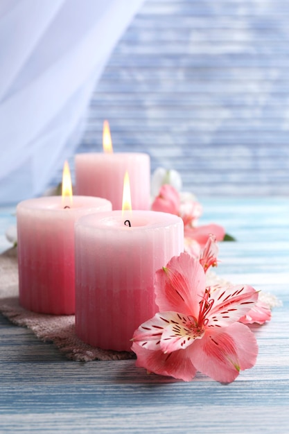 Hermosas velas con flores sobre fondo de madera