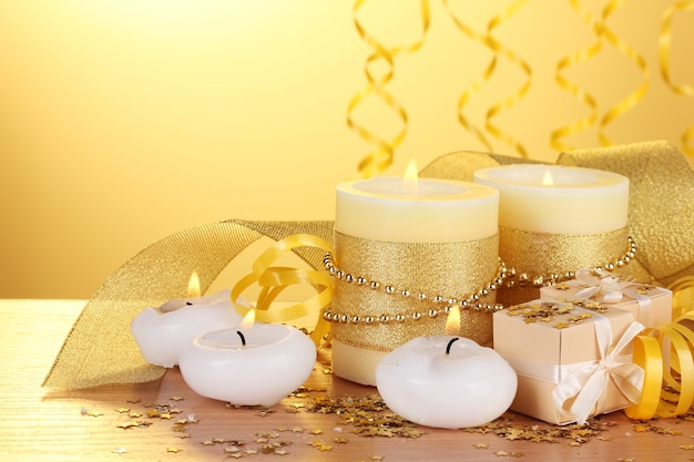 Hermosas velas, regalos y decoración de mesa de madera sobre fondo amarillo