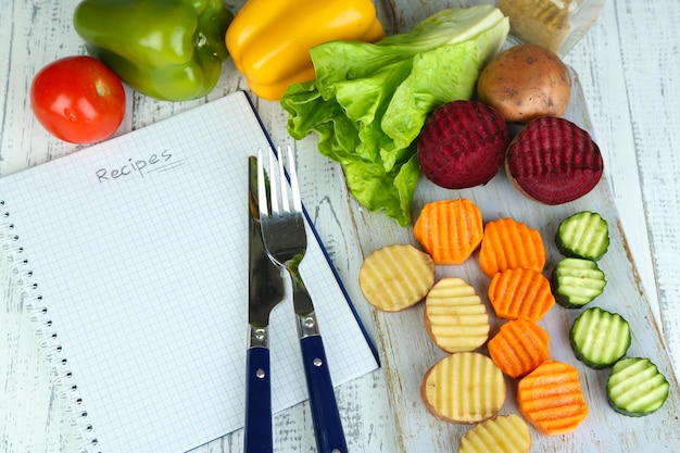 Foto hermosas verduras en rodajas en la tabla de cortar sobre fondo de color