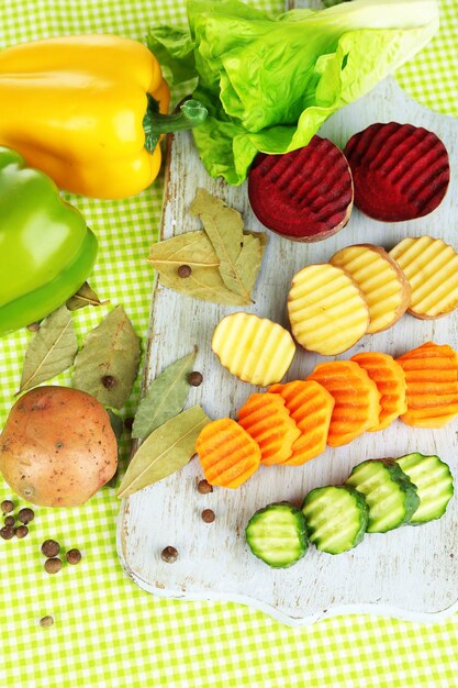 Hermosas verduras en rodajas en la tabla de cortar sobre fondo de color