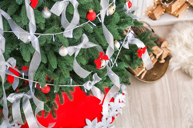 Hermoso abeto con cintas plateadas y luces de Navidad en la habitación