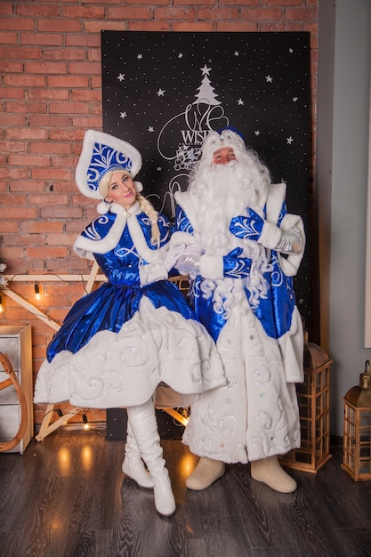 Hermoso abuelo Frost y Snegurochka en abrigos de piel azul cerca del árbol de Navidad