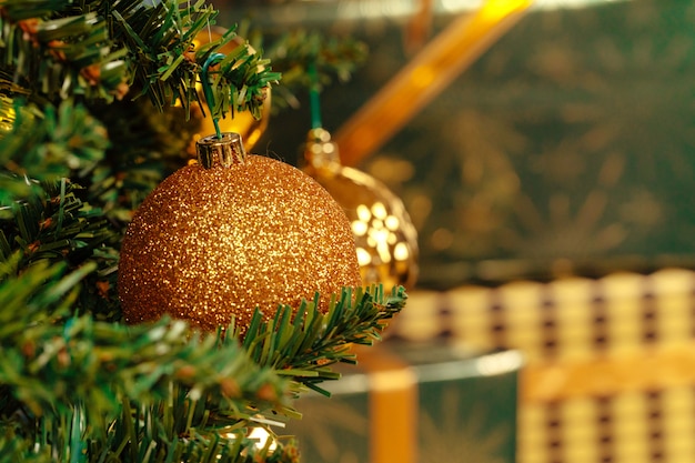 Hermoso adorno de oro colgando de un árbol de Navidad