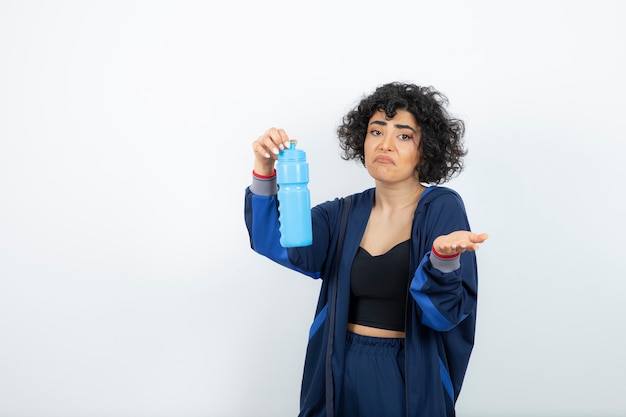 Hermoso ajuste deportivo mujer sosteniendo una botella de agua azul.