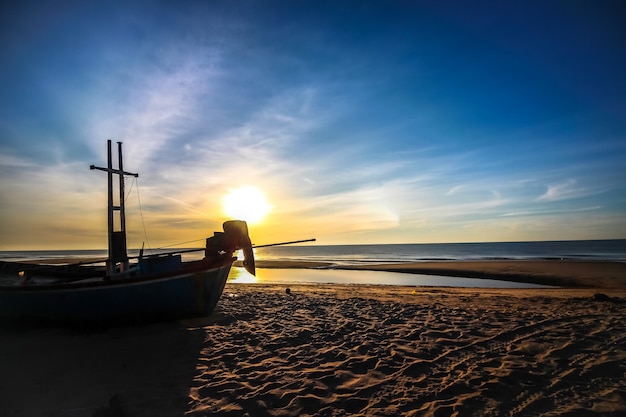 Hermoso amanecer al atardecer en la playa con bote silueta