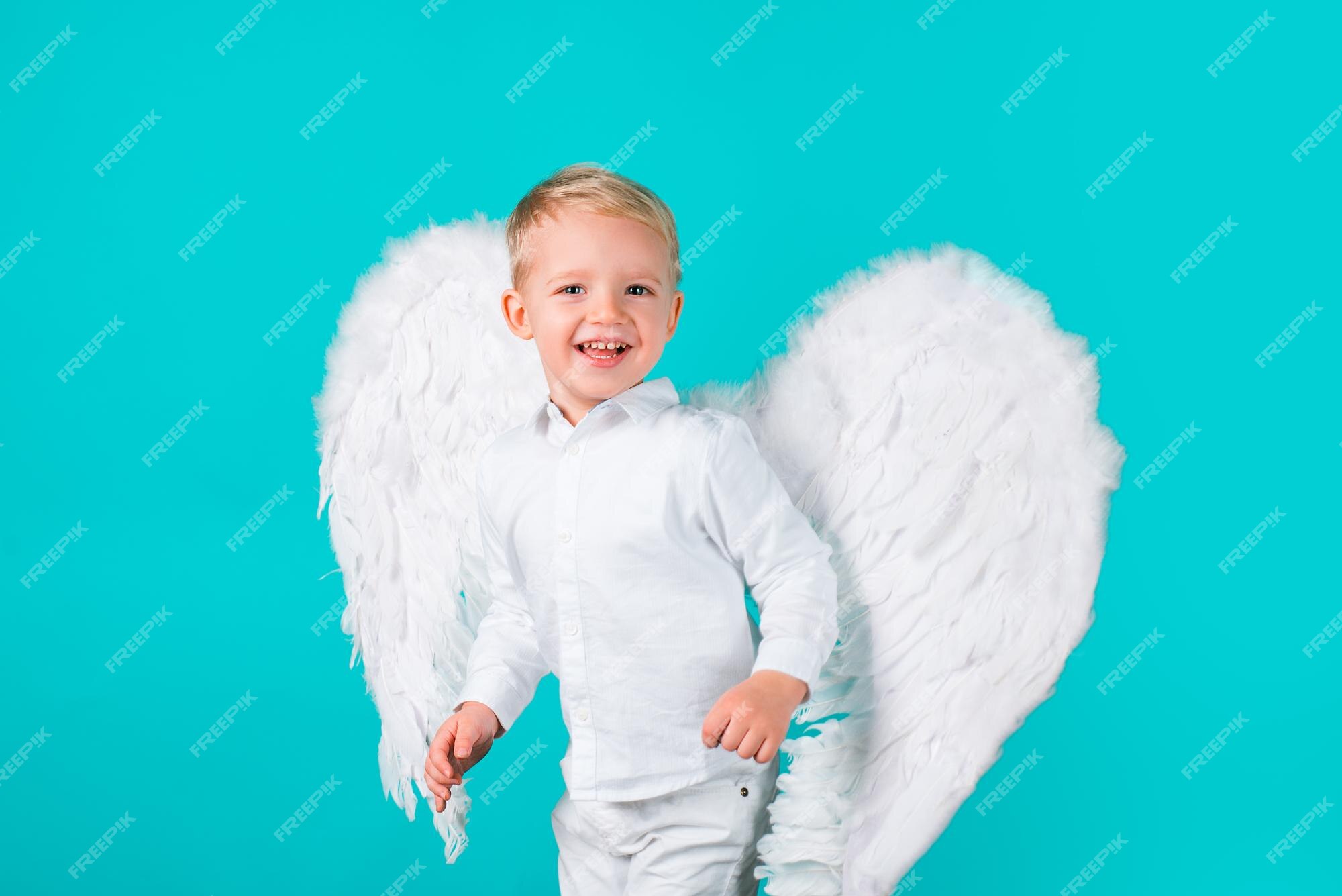 Hermoso angelito aislado de san valentín niño lindo niño vestido blanco de pie sobre fondo azul | Foto Premium