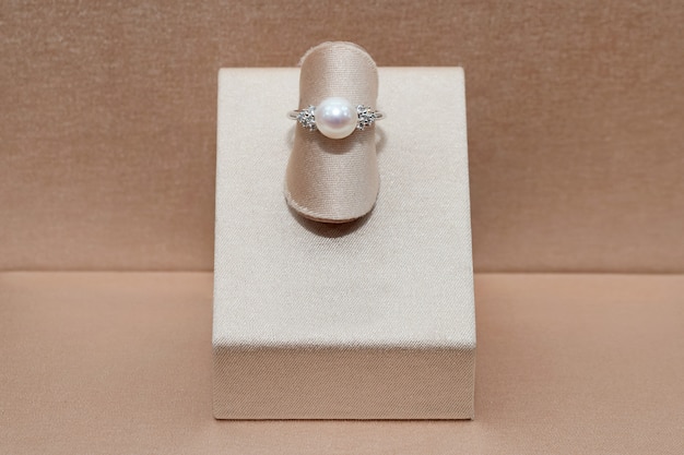 Hermoso anillo de oro y diamantes con esfera de brillo perla que se muestra en un soporte. Joyas de lujo