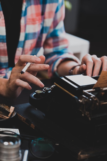 Un hermoso y antiguo primer plano de la máquina de escribir retro, las manos y una taza de café