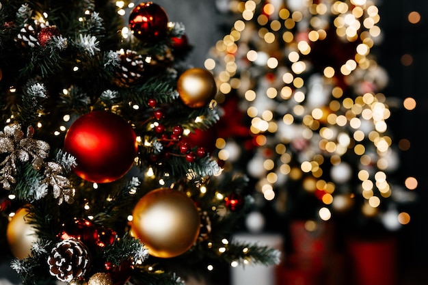 Hermoso árbol de Navidad con decoración festiva de oro rojo contra luces borrosas en primer plano de fondo