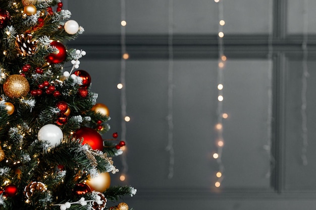 Hermoso árbol de Navidad con decoración festiva de oro rojo contra luces borrosas en primer plano de fondo