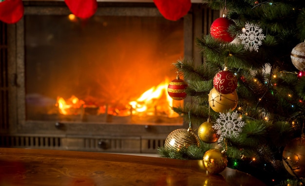 Hermoso árbol de Navidad decorado junto a la chimenea con troncos naturales