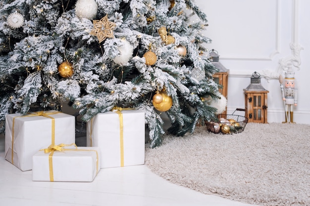 Hermoso árbol de Navidad dorado decorado en interior clásico de lujo blanco.