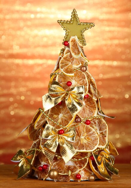 Hermoso árbol de navidad de limones secos con decoración, sobre fondo de brillo