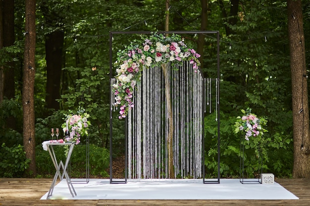 Hermoso arco de boda para ceremonia en estilo rústico ubicado en bosque