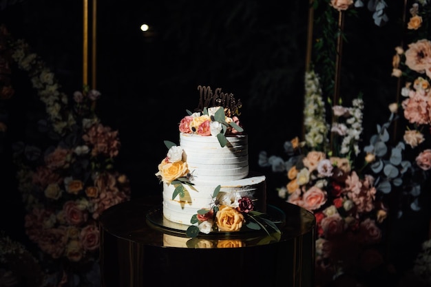 Hermoso arco de bodas con flores y un gran pastel de bodas