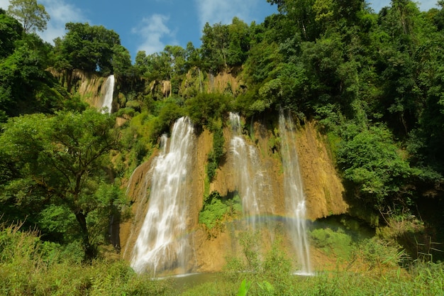 Hermoso arco iris de cascadas fluyen desde la montaña en verano.