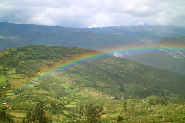 Hermoso arco iris sobre la vista del pueblo en la cima de la montaña desde la antigua ciudadela de Kuelap, norte de Perú