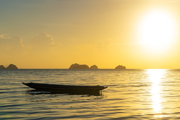 Hermoso atardecer en la costa de una isla tropical en Tailandia, la silueta de un barco en el océano.