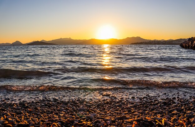 Hermoso atardecer en la costa mediterránea con islas y montañas de piedras en la playa iluminada por