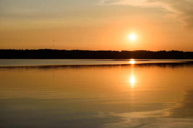 Hermoso atardecer dorado en el lago, siluetas negras de la orilla. La hermosa naturaleza que lo rodea.