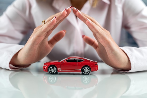 Hermoso auto pequeño en manos de una mujer en la mesa