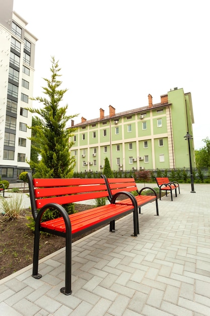 Hermoso banco de madera roja en el patio de un nuevo edificio residencial