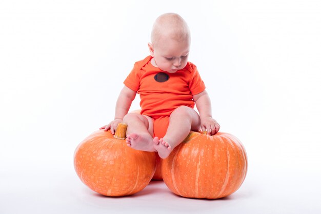 Hermoso bebé en camiseta naranja sobre un fondo blanco.