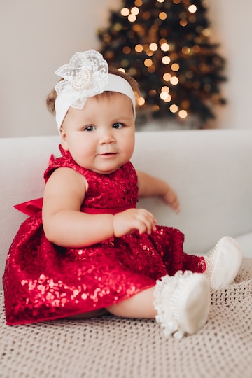 bebé caucásico vestido rojo se sienta cerca del árbol navidad en | Foto Premium