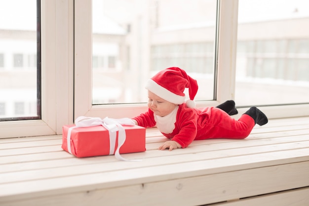 Hermoso bebé celebra la Navidad. Vacaciones de año nuevo. Bebé disfrazado de Navidad y gorro de Papá Noel.