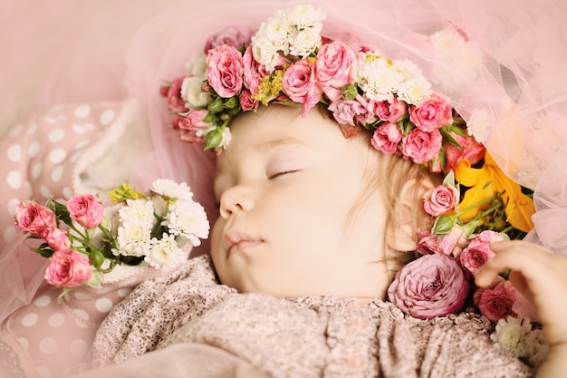 Hermoso bebé con flores y accesorios.